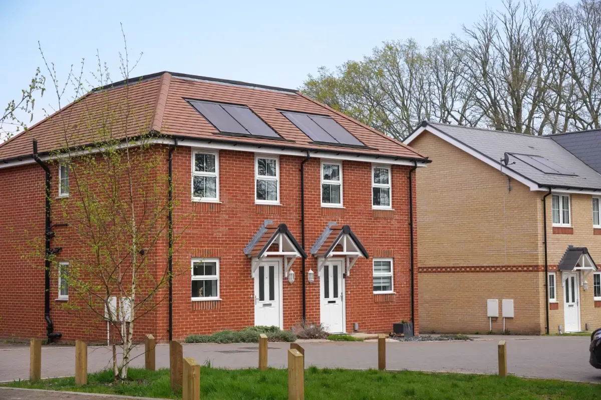 Core One Construction | Two-story brick houses with solar panels on a red tiled roof, trees in the background, and wooden posts in the foreground.