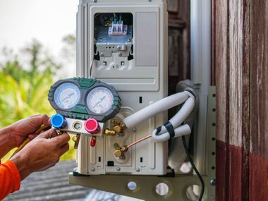 Technician adjusts electrical meter and gauge box with colorful dials outdoors