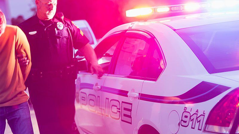 man being arrested outside of police car