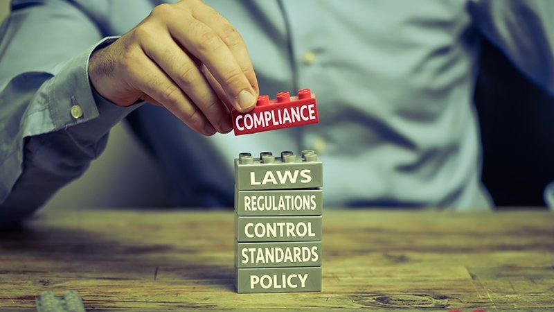 man stacking legos with words like compliance, laws, regulations and control written on them - marijuana compliance practice area image