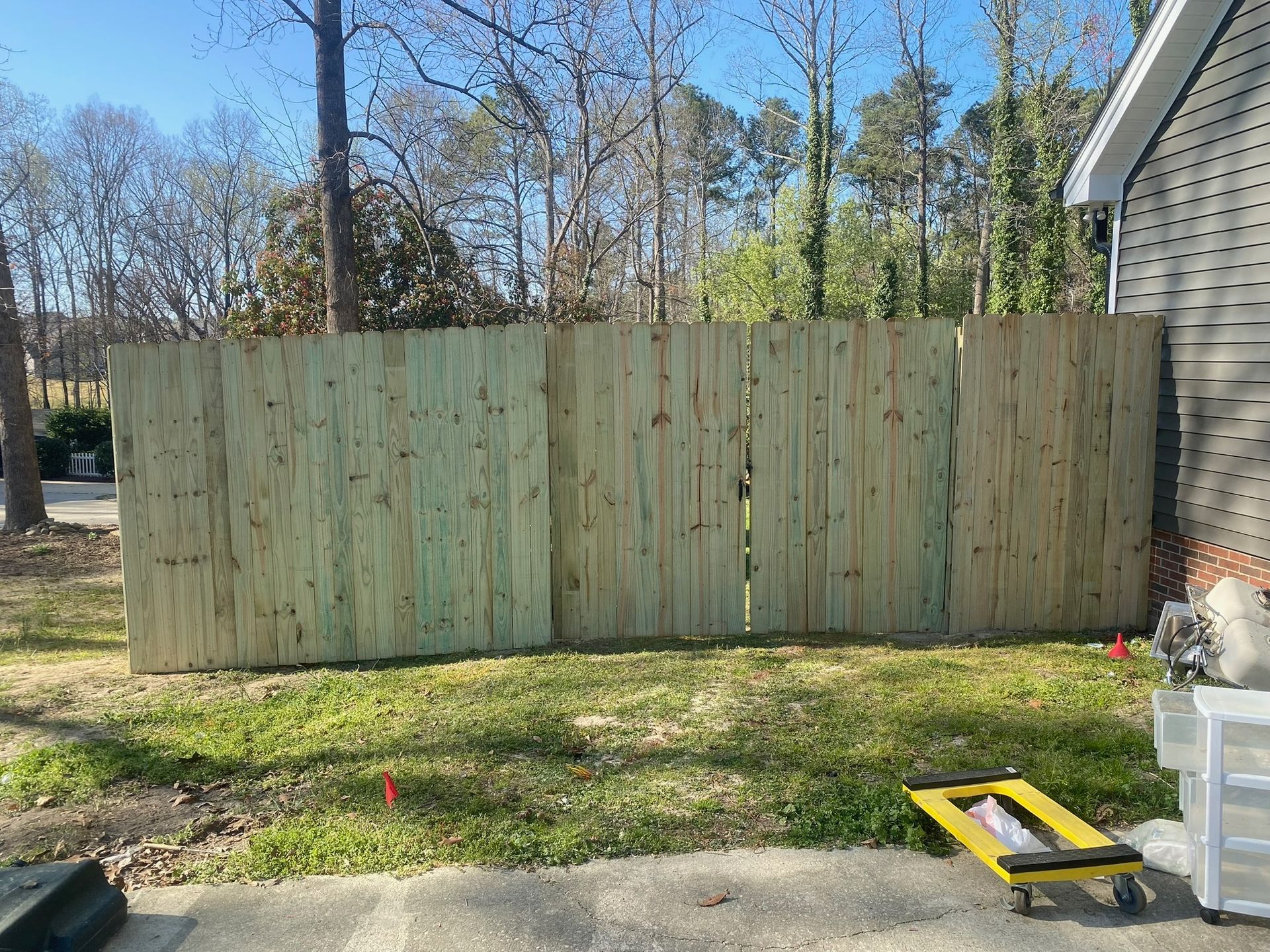 A wooden fence is being built in the backyard of a house.