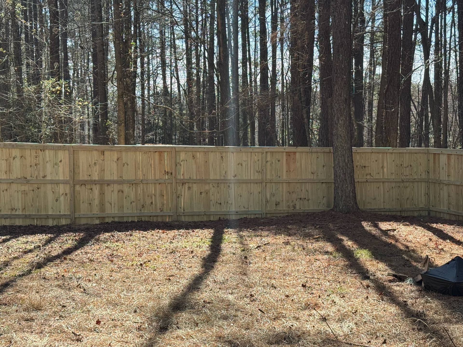 A wooden fence is in the middle of a forest.