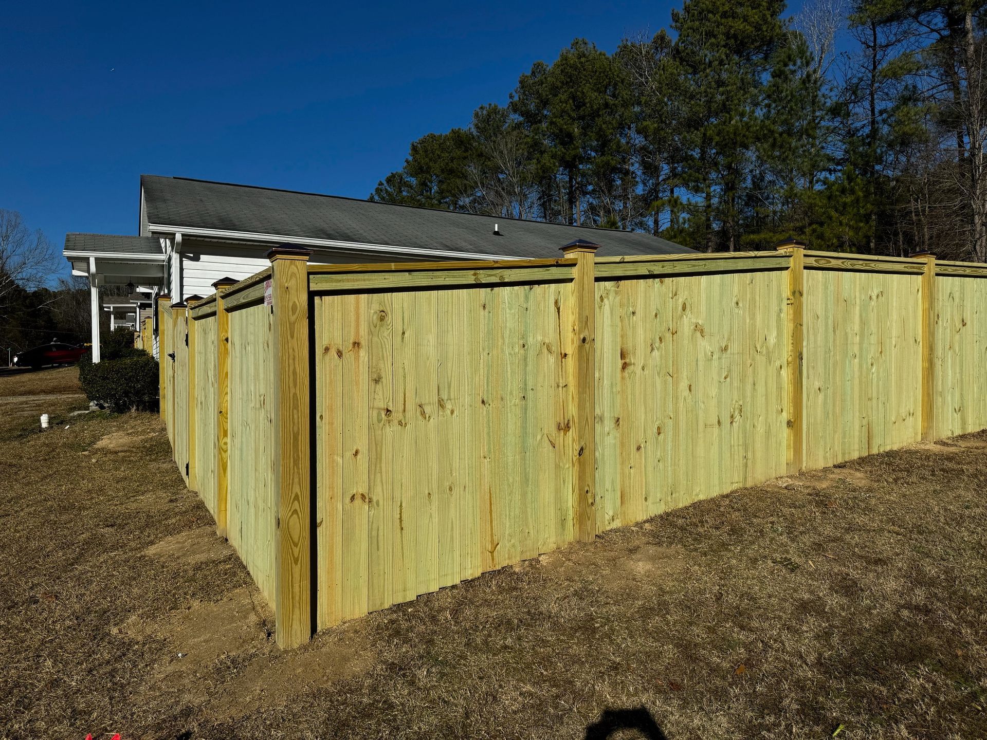 A wooden fence is in the backyard of a house.