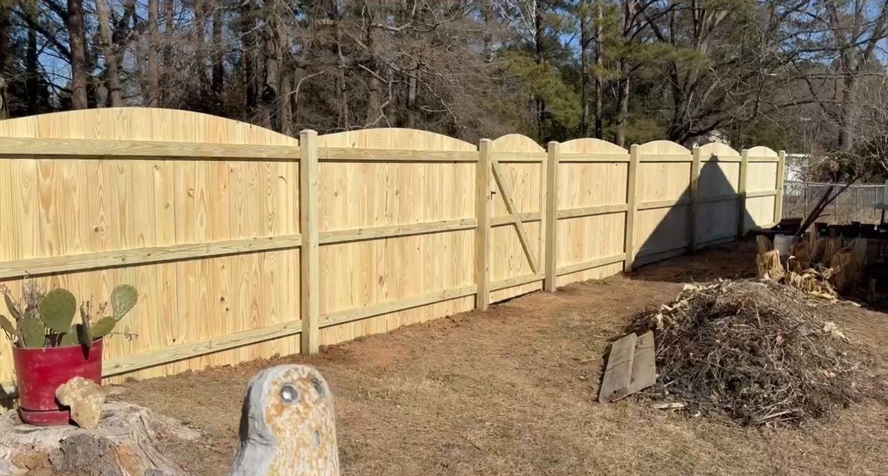 A wooden fence is in the backyard of a house.