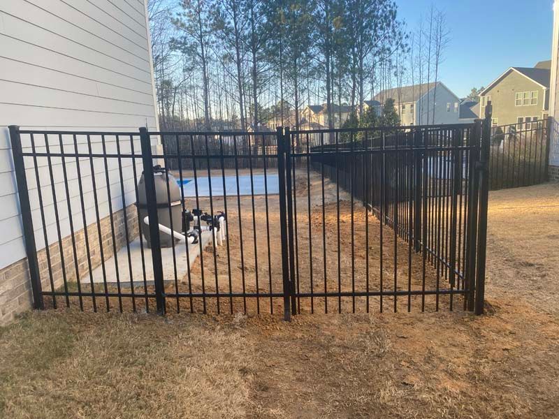 A wooden fence with a gate in front of a house.