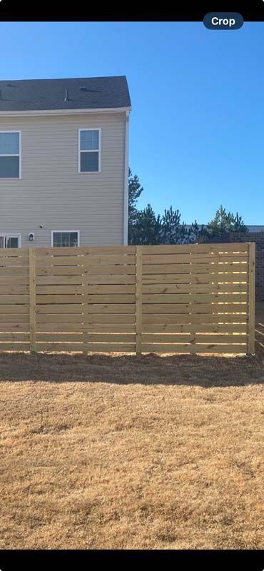 A wooden fence with a gate in front of a house.