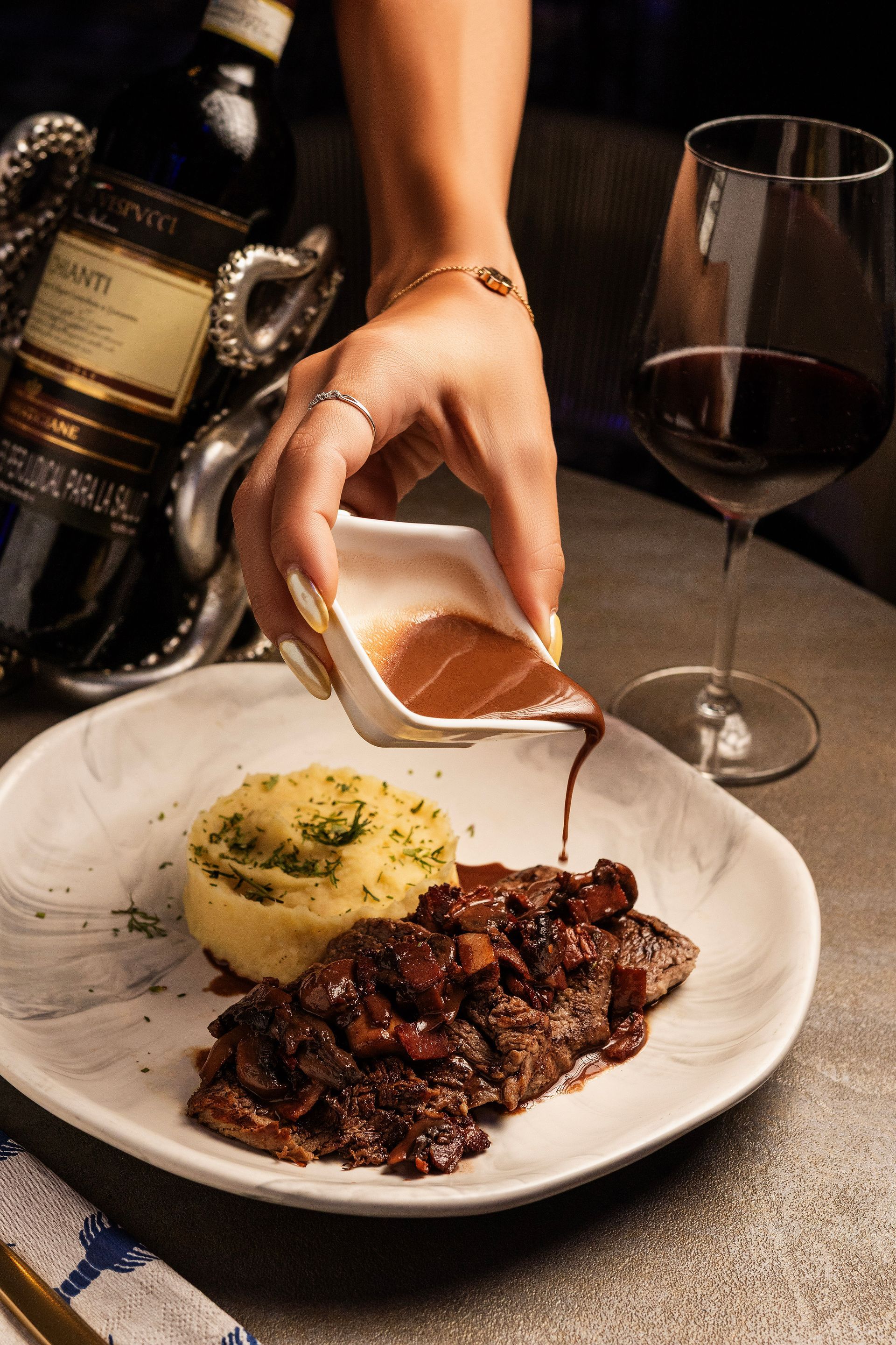 Filete emplatado con verduras asadas y salsa sobre una mesa de madera junto a una ventana.