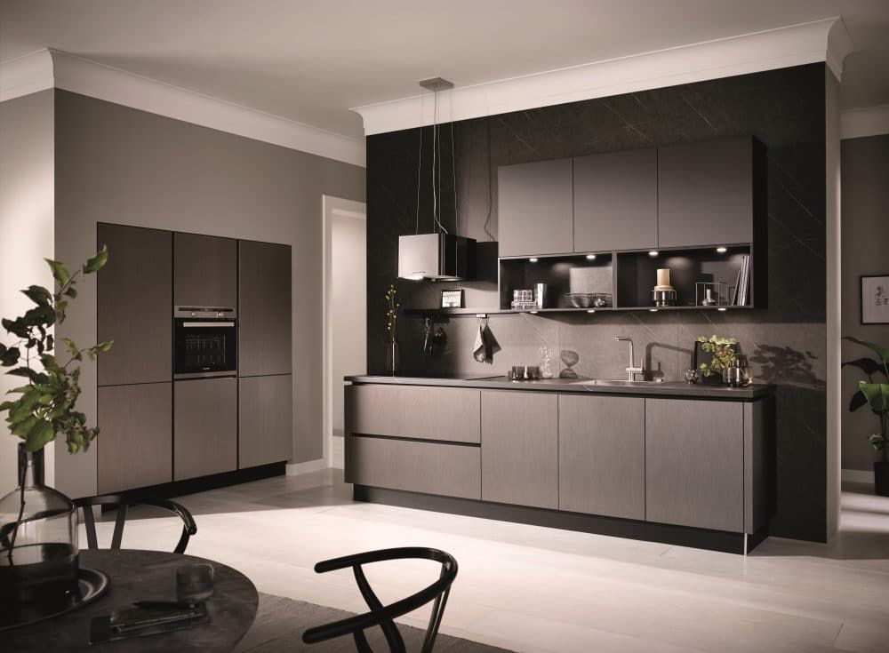 Moderne graue Küche mit eleganten Schränken, Kochinsel und dunkler Akzentwand in einem minimalistischen Interieur