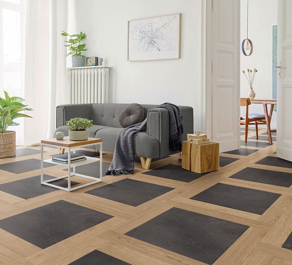 Modernes Wohnzimmer mit grauem Sofa, schwarz-braunem geometrischem Teppich, Couchtisch, Pflanzen und Holzelementen
