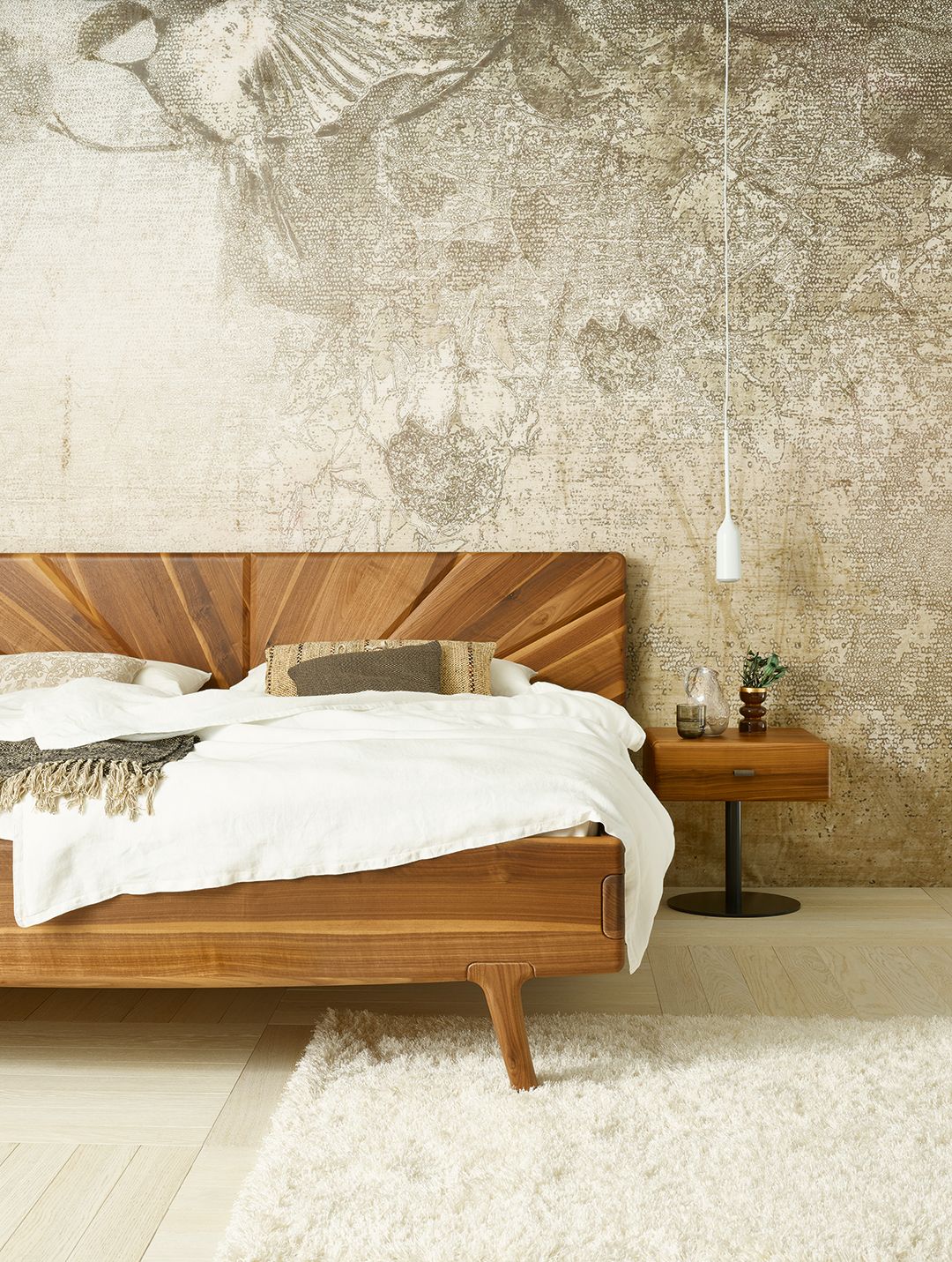 Modernes Schlafzimmer mit Holzbett, weißer Bettwäsche, Nachttisch und gemusterter Tapete.