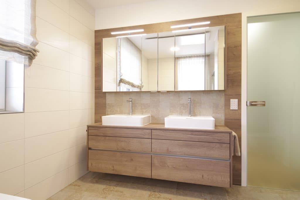 Modernes Badezimmer mit Doppelwaschtisch aus Holz, zwei Waschbecken, großem Spiegel und Milchglastür