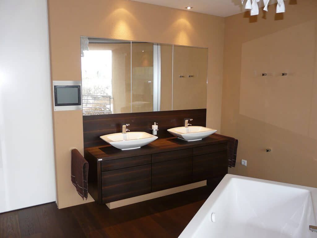 Modernes Badezimmer mit Doppelwaschbecken, großem Spiegel, beigefarbenen Wänden und einer Badewanne im Vordergrund