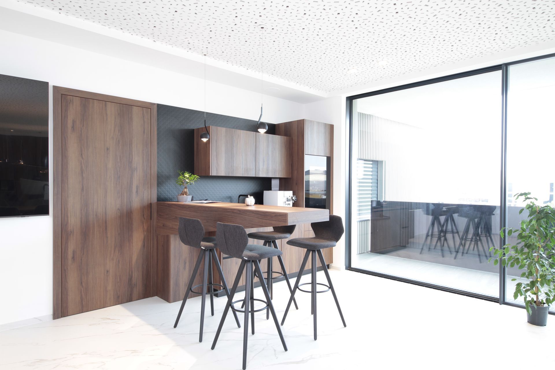Moderne Küche und Essbereich mit Holzschränken, schwarzen Barhockern und einer Glaswand, die sich zu einem Balkon öffnet.