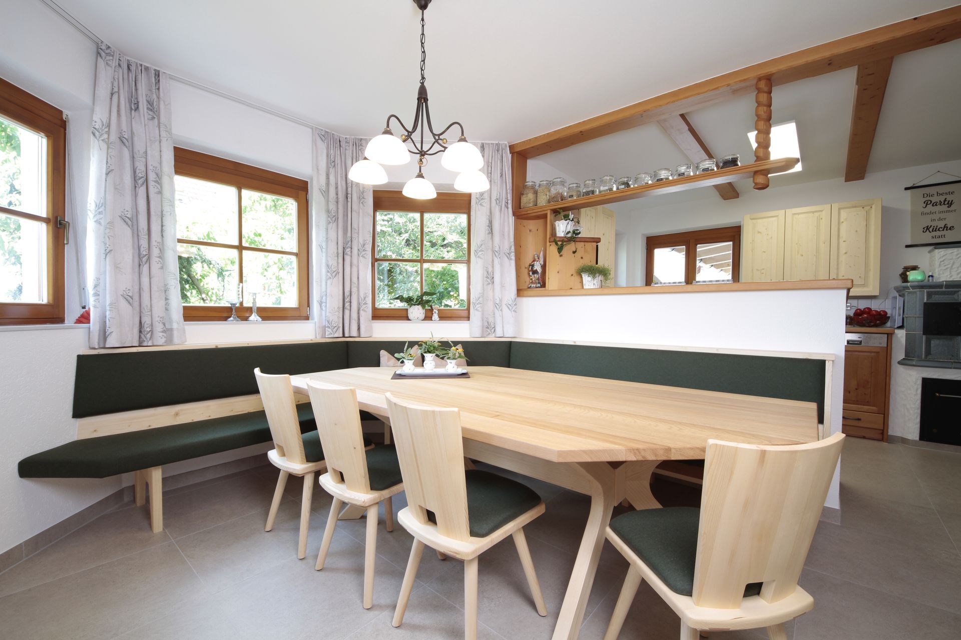 Helles Esszimmer mit Holztisch, Stühlen, Sitzbank und Küche im Hintergrund