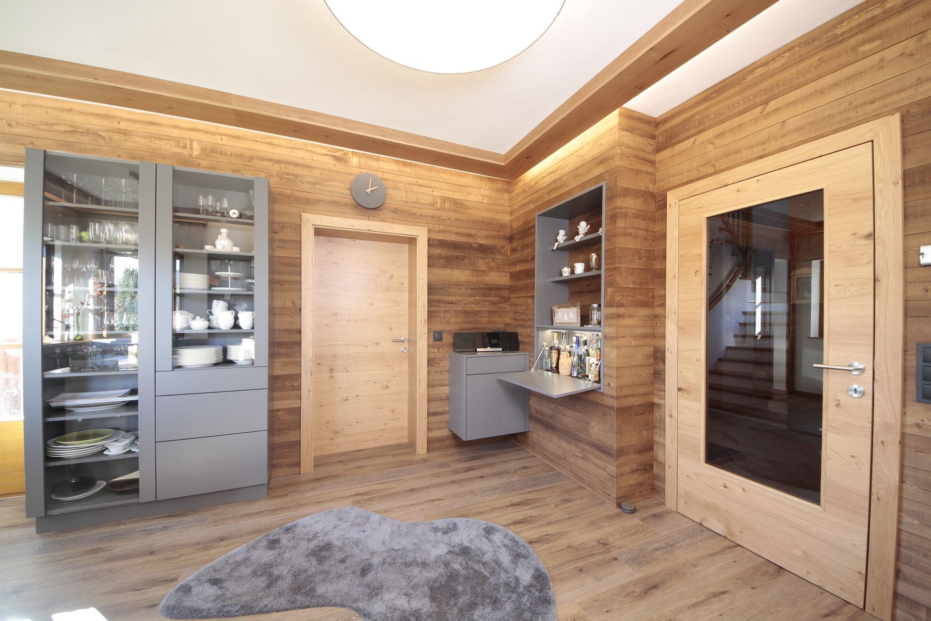 Holzvertäfelte Sauna mit Glasschränken, Holztür, Steinboden und warmem Deckenlicht