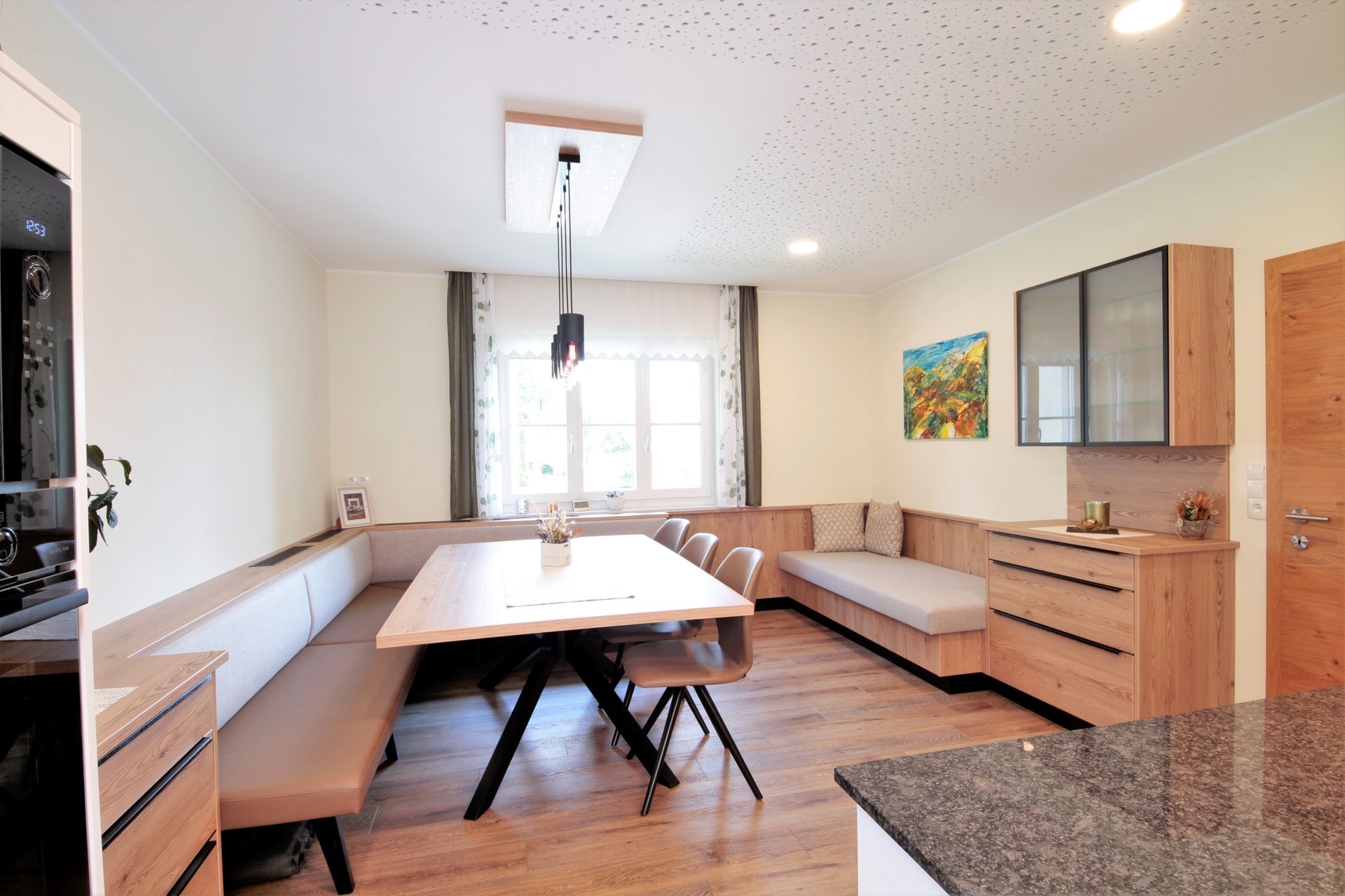 Helles Esszimmer mit langem Holztisch, Bänken, Pendelleuchte und großem Fenster.