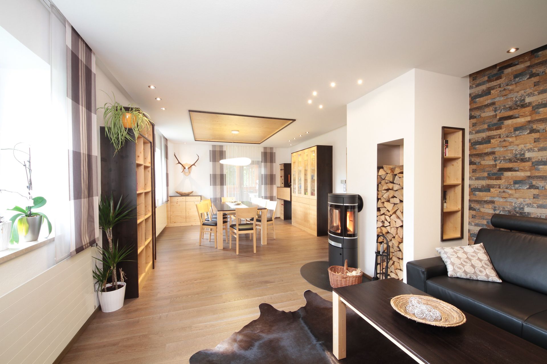 Helles, modernes Wohnzimmer mit Kamin, Essbereich, Ledersofa und großen Fenstern