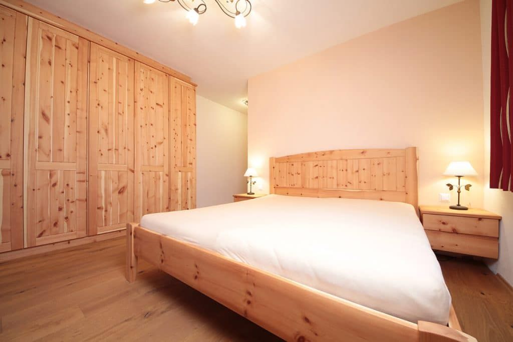 Helles Schlafzimmer mit Holzbett, Kleiderschränken, Nachttischlampen und cremefarbenen Wänden