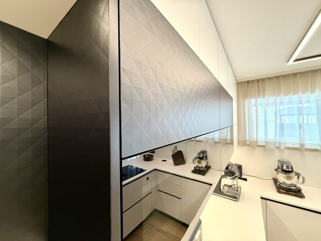 Moderne Luxusküche mit glänzenden schwarz-weißen Schränken, Kochinsel mit Sitzgelegenheiten