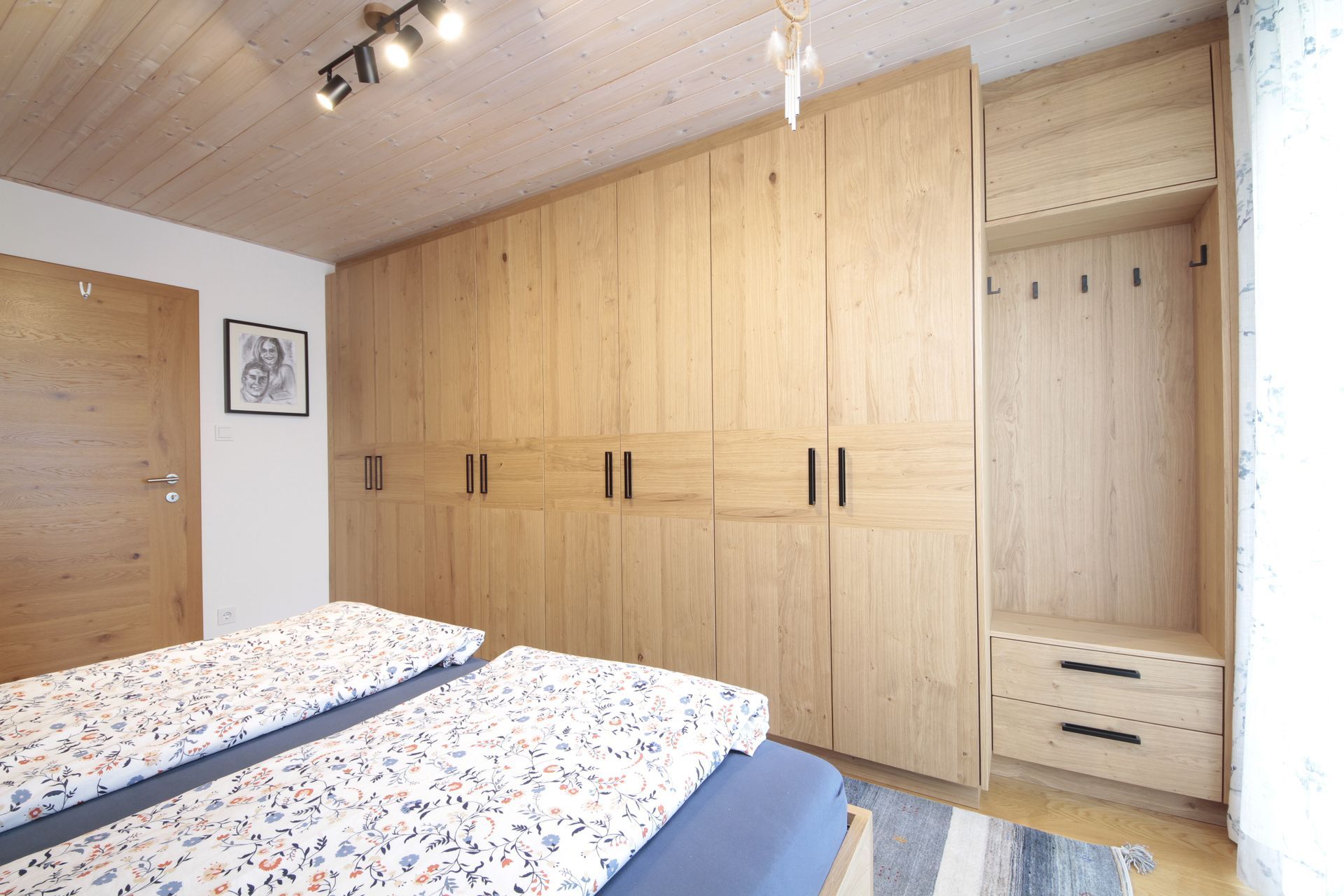 Schlafzimmer mit großen, eingebauten Holzschränken, zwei Einzelbetten und einer kleinen, offenen Schranknische.