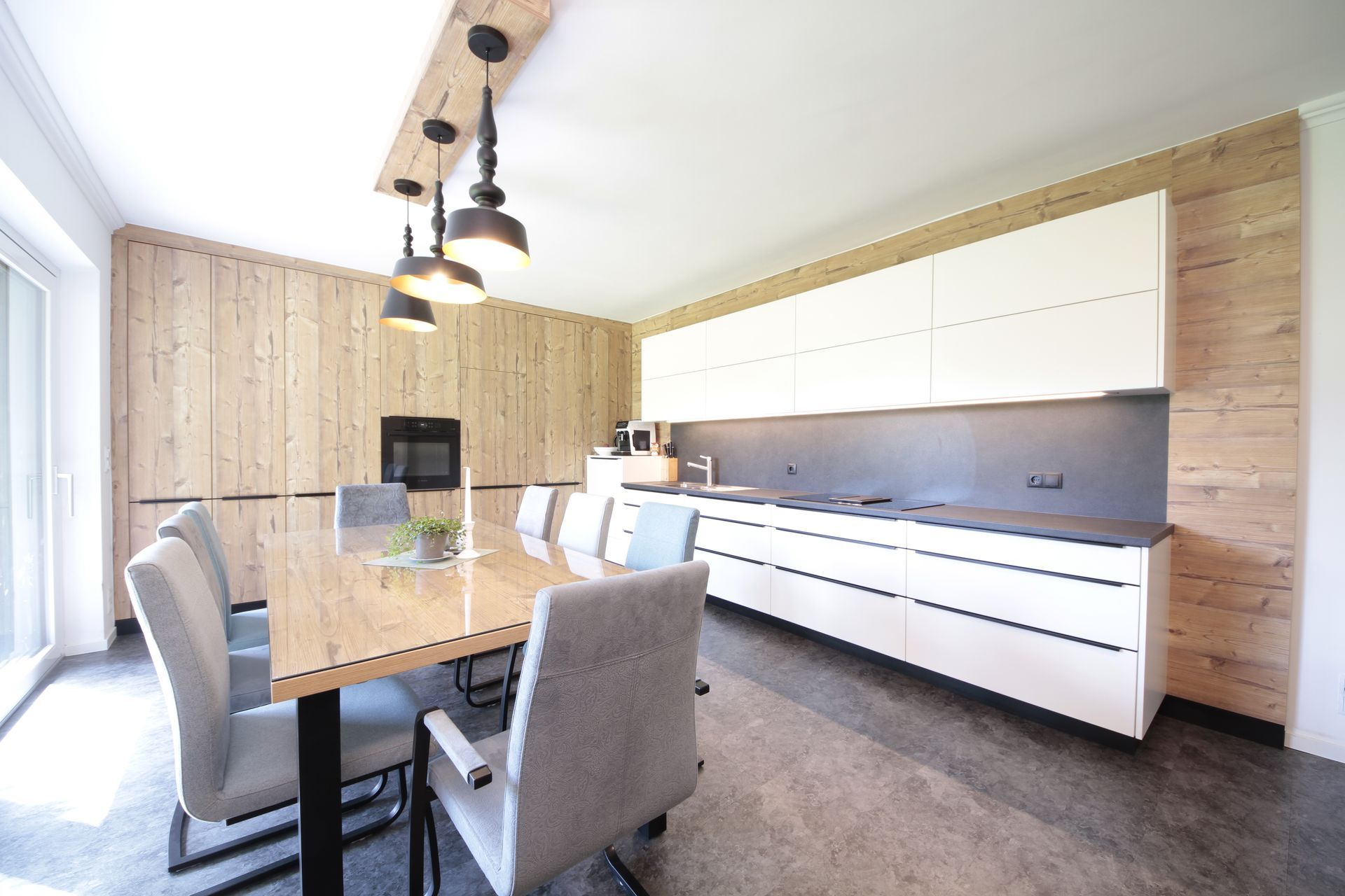Moderner Essbereich mit Glastisch, grauen Stühlen und einem langen weißen Sideboard unter Pendelleuchten