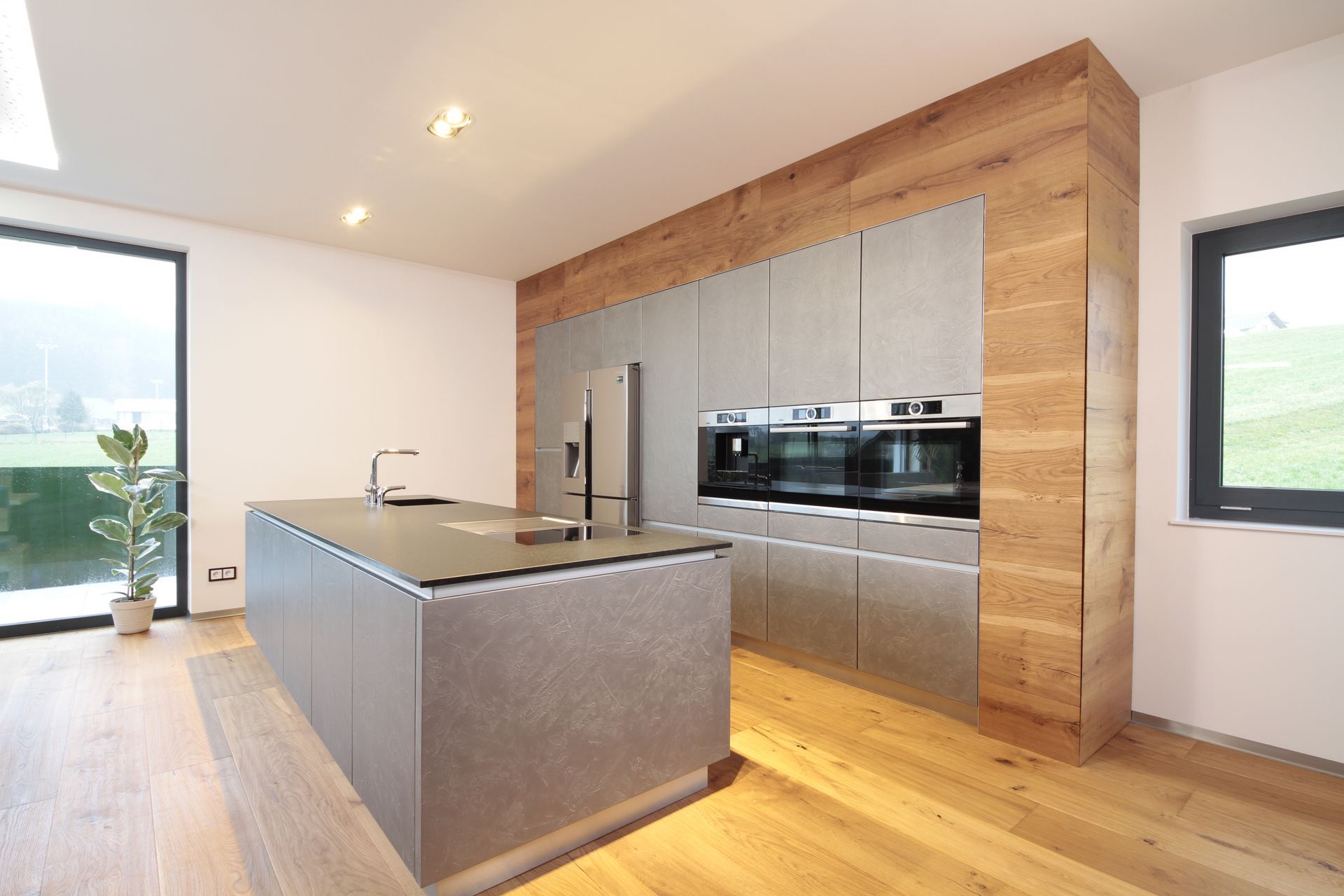 Moderne Küche mit grauer Kochinsel, Holzboden und eingebauten Edelstahlgeräten