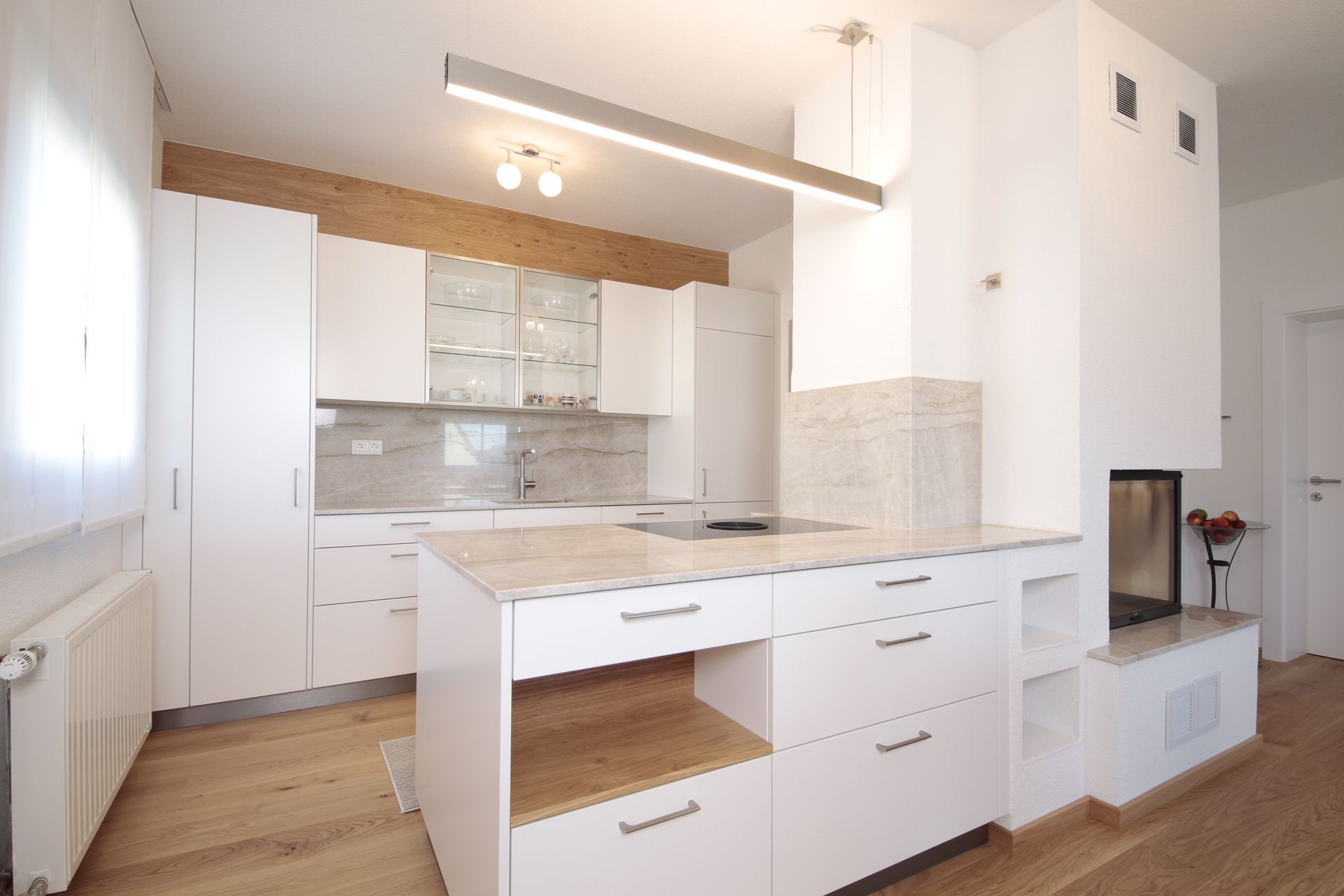 Helle, moderne weiße Küche mit Kochinsel, Holzboden und Einbaugeräten
