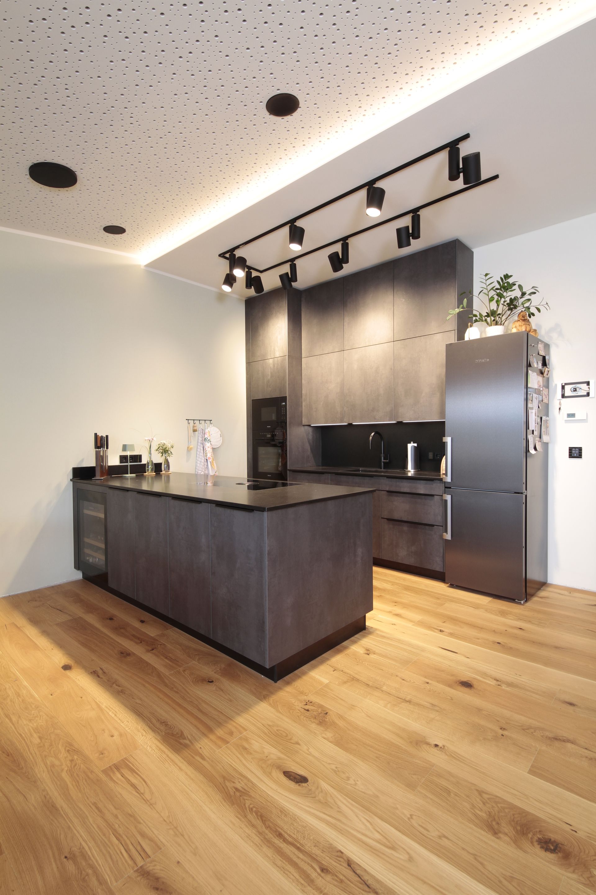 Moderne Küche mit dunkler Holzinsel, Edelstahlkühlschrank und warmem Holzboden