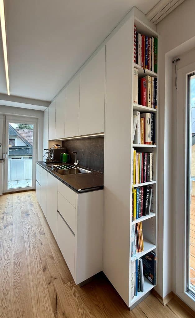 Schmaler Flur mit eingebauten weißen Regalen für Bücher und einer kleinen Küchentheke.