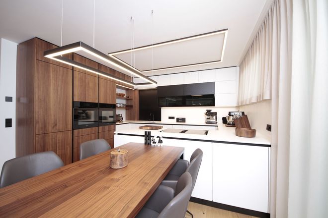 Moderne Küche und Essbereich mit Holztisch, grauen Stühlen, weißen Schränken und Einbaugeräten