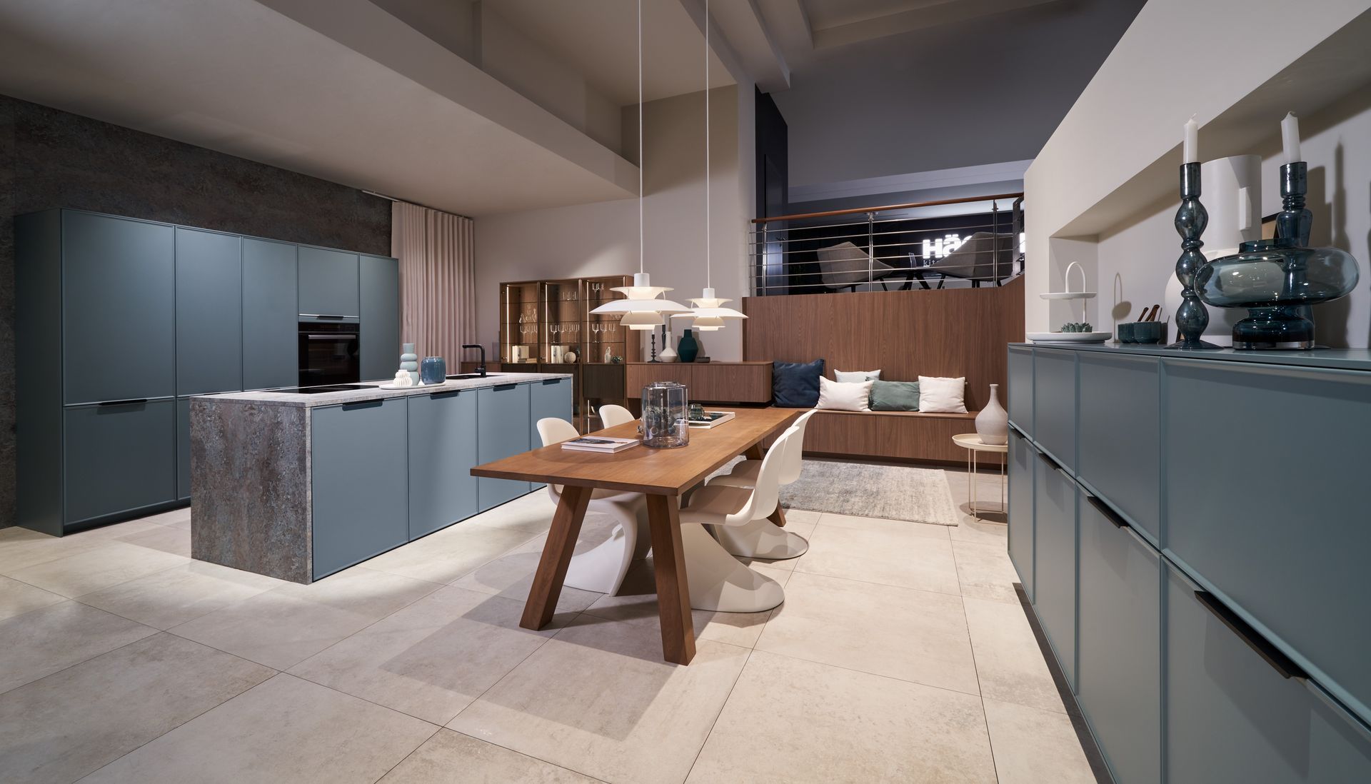 Moderne Küche und Essbereich mit blauen Schränken, Holztisch und Pendelleuchten