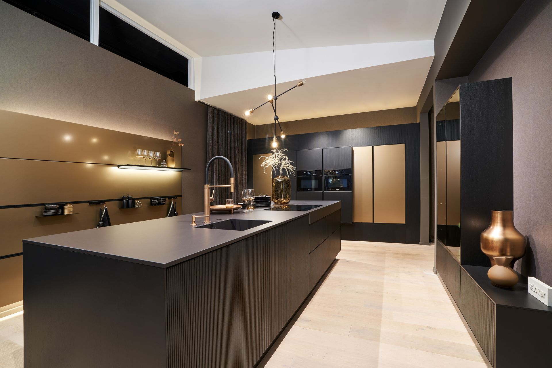 Moderne Küche in Schwarz und Beige mit langer Kochinsel, Pendelleuchten und eleganten Einbauschränken.
