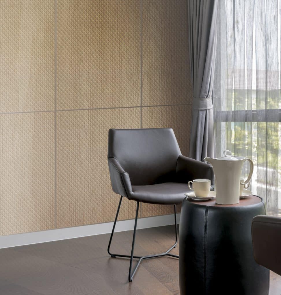 Moderner Loungesessel neben einem kleinen Tisch und einer Karaffe an einem sonnendurchfluteten Fenster