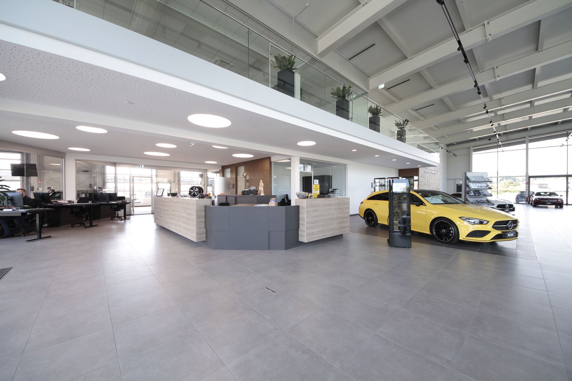 Moderner Autohaus-Showroom mit einem gelben Sportwagen, offenem Arbeitsbereich und heller Showroom-Beleuchtung