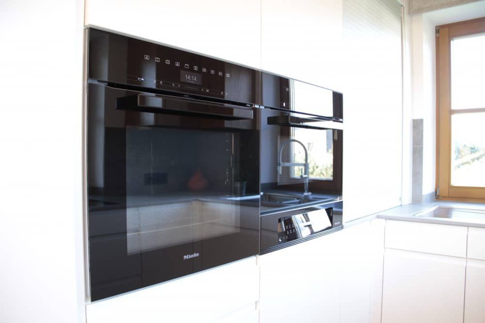 Schwarzer Einbau-Küchenbackofen und Mikrowelle in einer strahlend weißen Schrankwand