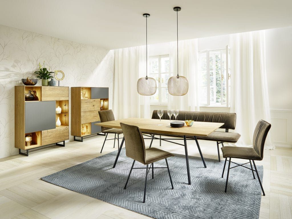 Modernes Esszimmer mit Holztisch, beigefarbenen Stühlen, Pendelleuchten, großem Teppich und hellen Vorhängen.