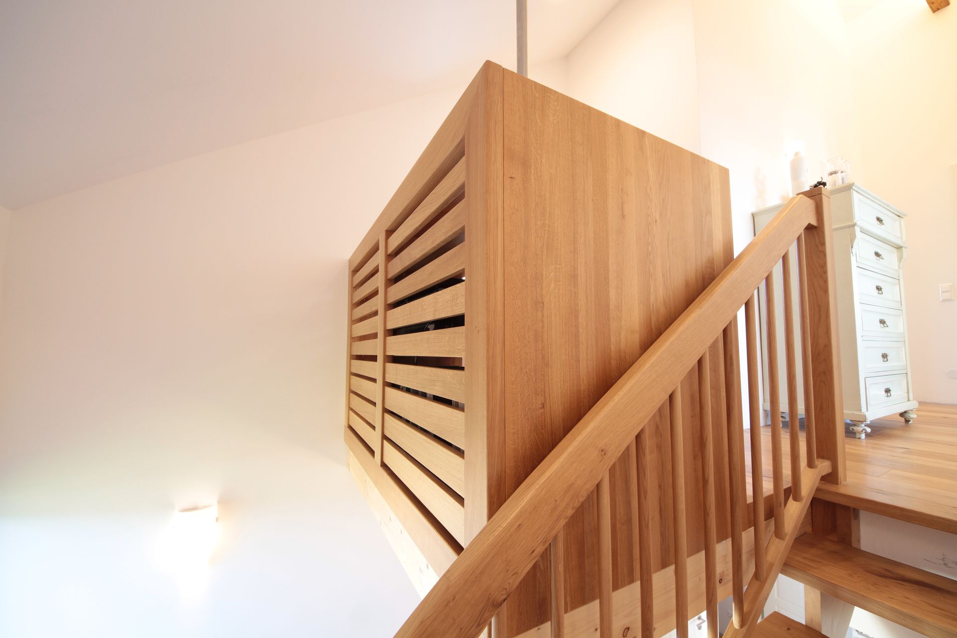 Holztreppe mit Lattengeländer in einem hellen Innentreppenabsatz