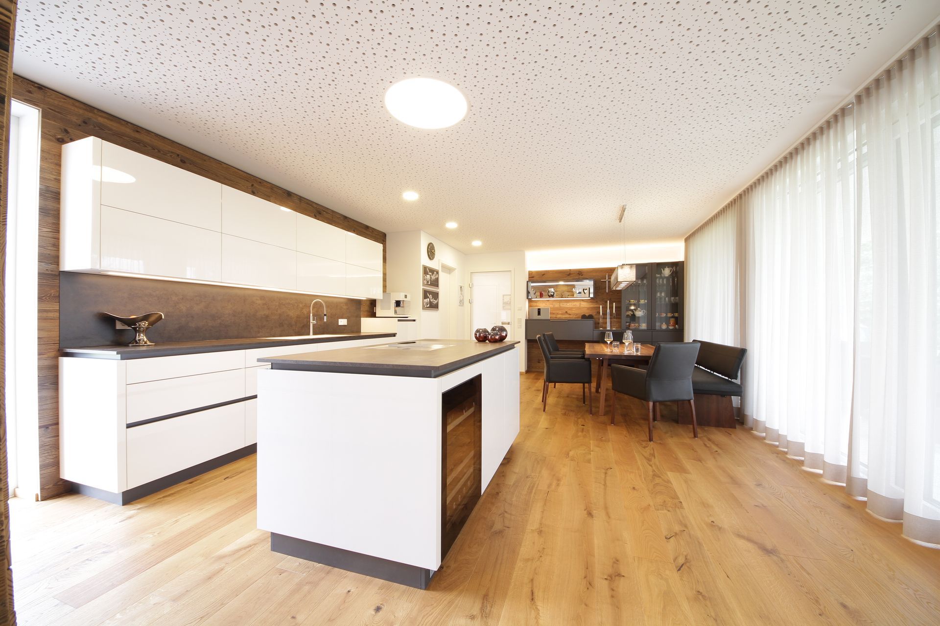 Helle, moderne Küche und Essbereich mit weißen Schränken, Holzböden und großen Fenstern