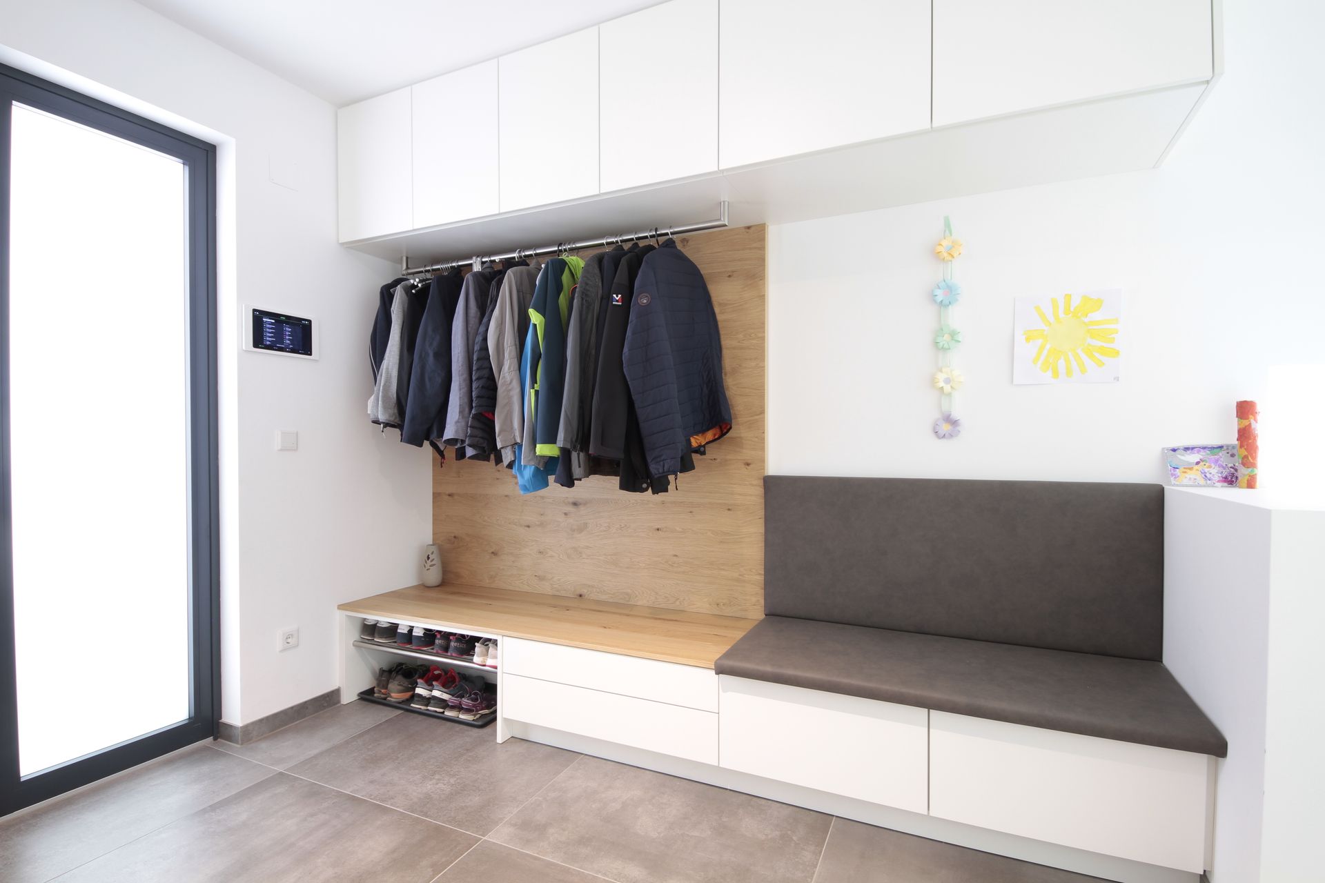 Moderner Eingangsbereich mit Garderobe, Sitzbank mit Stauraum und einer Tür mit Milchglaseinsatz