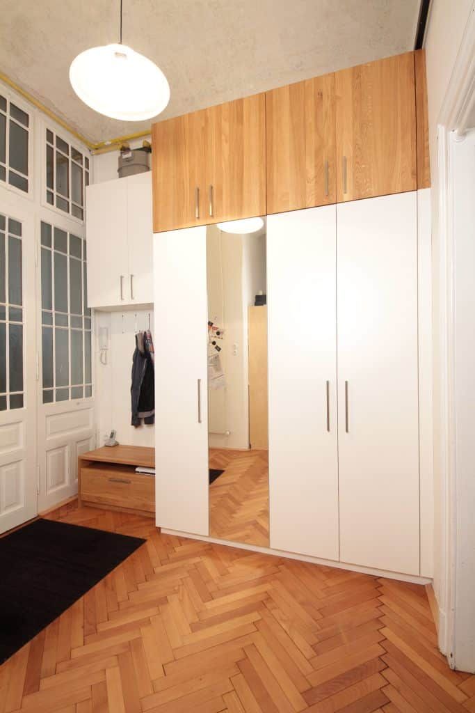 Moderner Eingangsbereich mit weißem Kleiderschrank, Holzschränken, Fischgrätparkett und Hängelampe