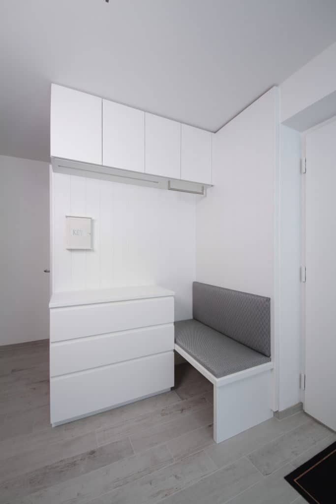 Weißer Eingangsbereich mit Einbauschränken, Schubladen, Sitzbank und Wandschrank in einem kleinen Flur