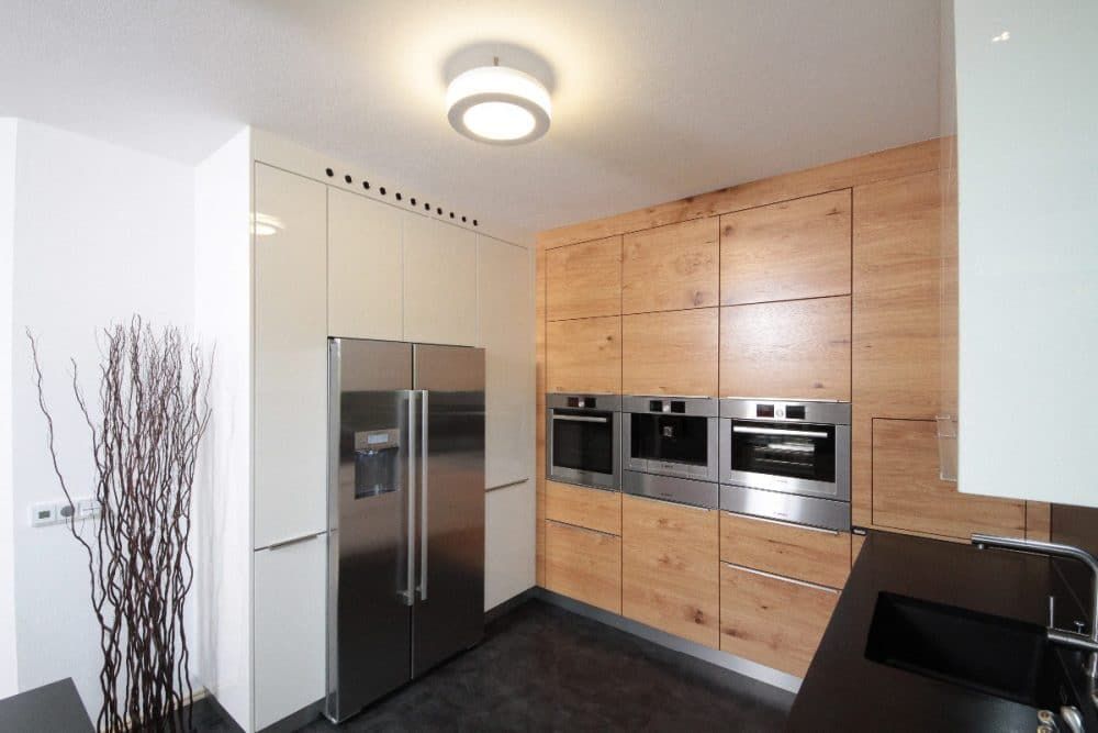 Moderne Küche mit Edelstahlkühlschrank, Holzschränken und Einbaubacköfen