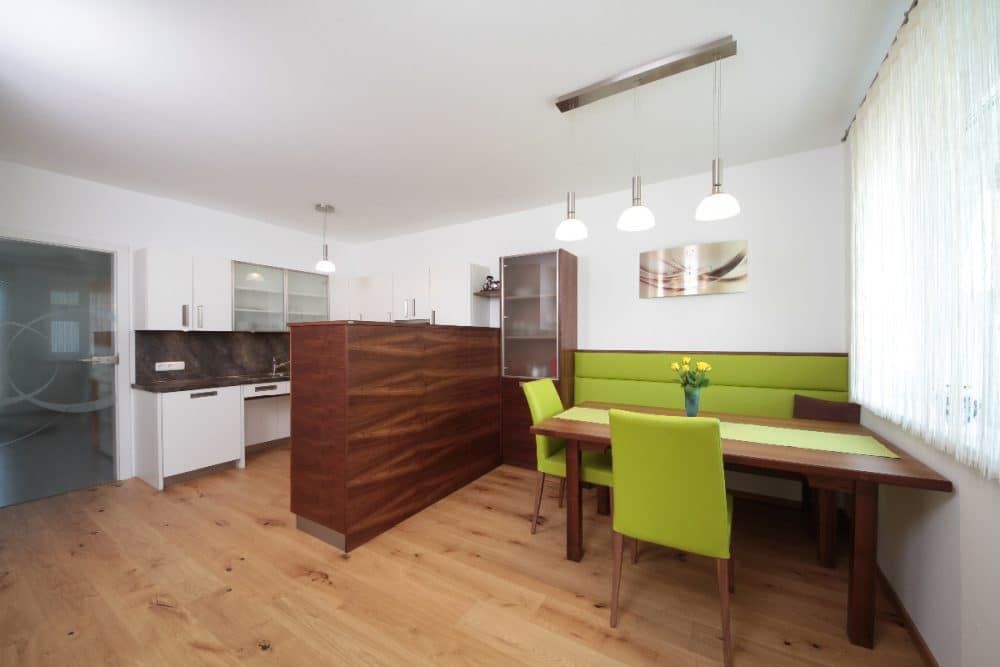 Heller, moderner Küchen- und Essbereich mit Holzboden, grüner Sitzbank und Holztisch