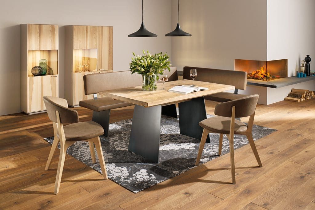 Modernes Esszimmer mit Holztisch, beigefarbenen Stühlen, schwarzen Pendelleuchten und einem Teppich auf Parkettboden