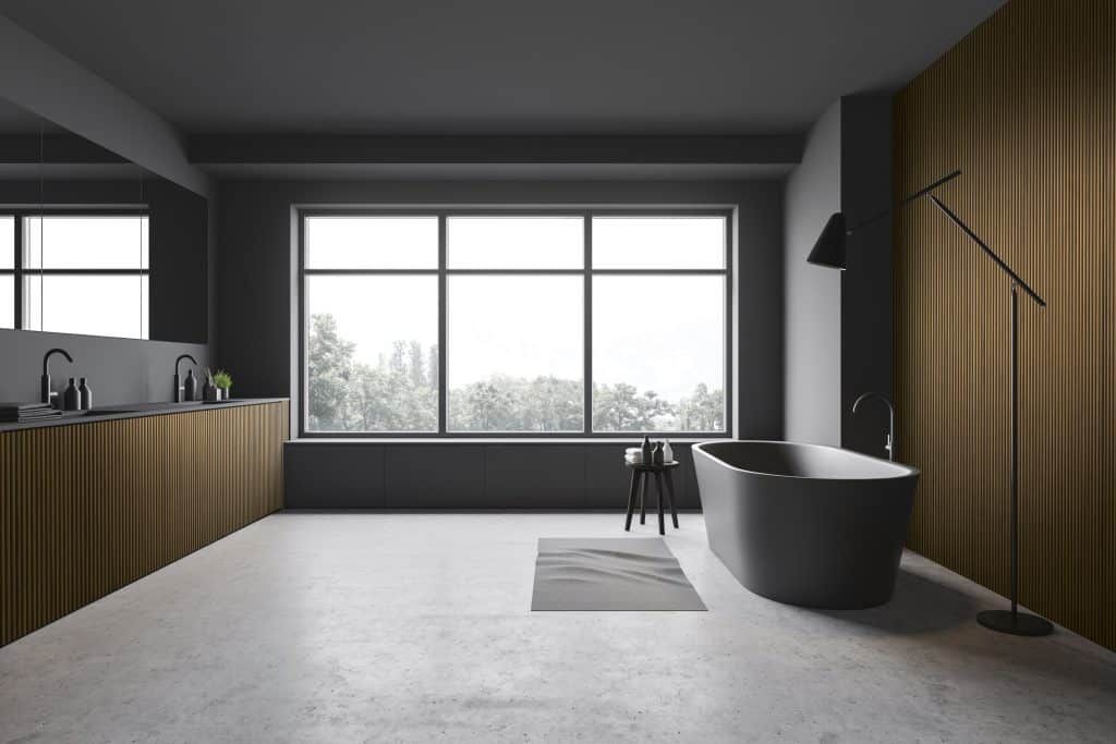 Modernes, minimalistisches Badezimmer mit großem Fenster, freistehender Badewanne und holzvertäfelter Wand