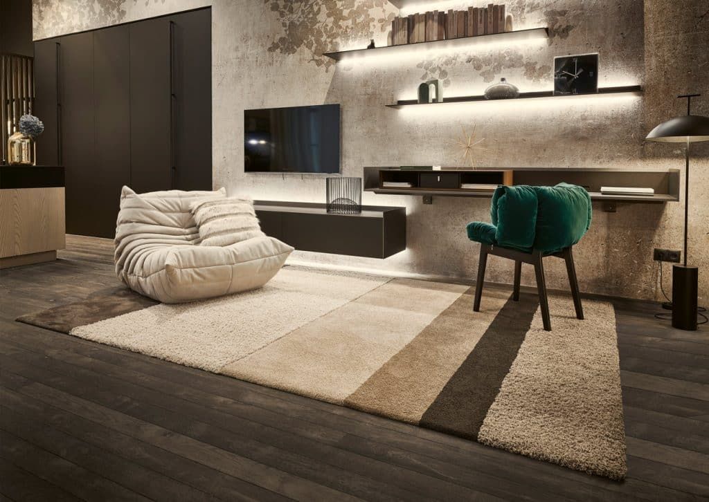 Modernes Wohnzimmer mit einem bequemen Sessel, einem an der Wand montierten Fernseher auf einem großen Teppich.