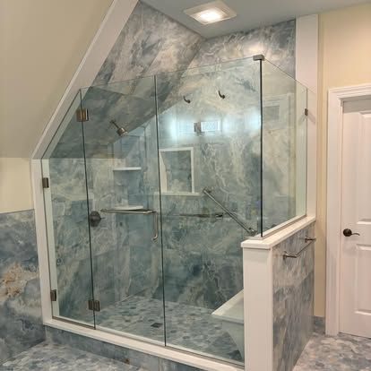 Black-framed glass shower with white subway tile walls and chrome showerhead in a bathroom.