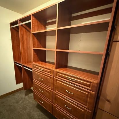 Built-in wooden closet with open shelves and drawers in a bedroom alcove.