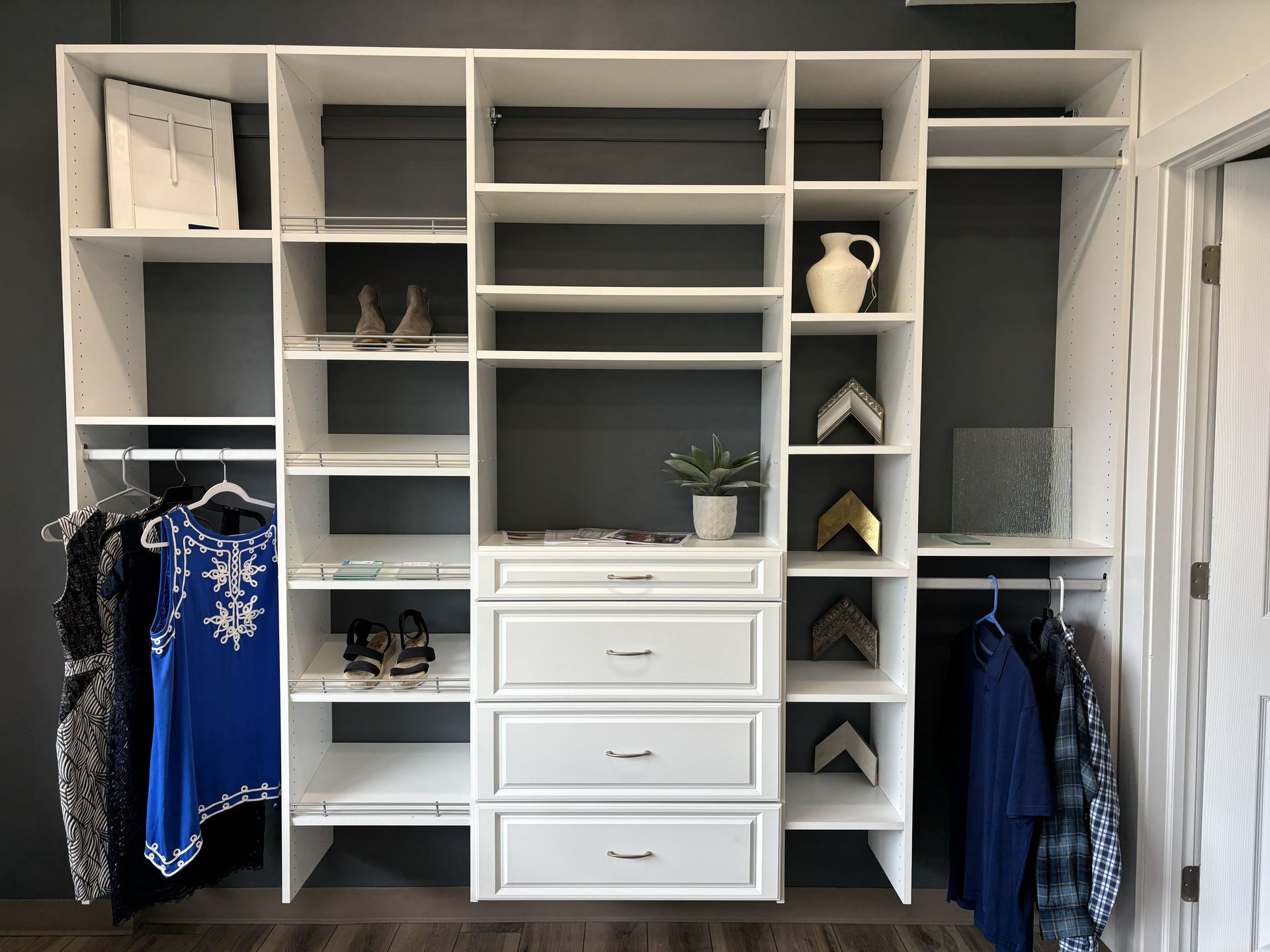 Walk-in closet with white shelving, drawers, hanging clothes, and shoes neatly organized