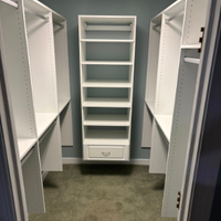 Walk-in closet with white built-in shelves and a single drawer on a carpeted floor.